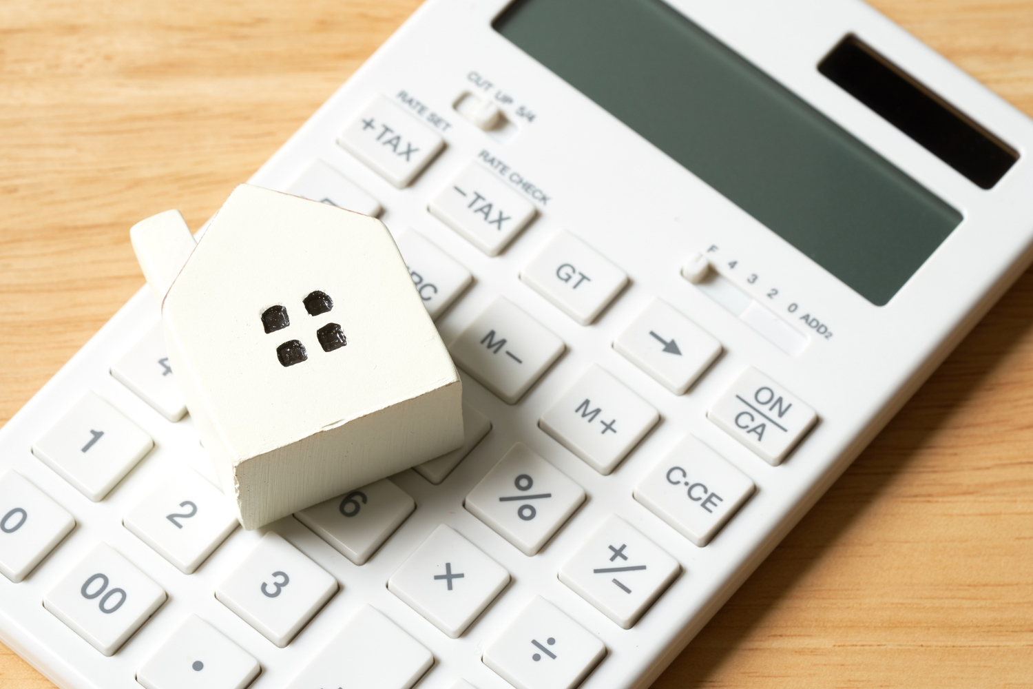 Un modèle de maison modèle est placé sur une calculatrice.